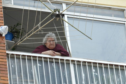 Una mujer mayor asomada a la terraza de su vivienda en la capital burgalesa.-ISRAEL L. MURILLO