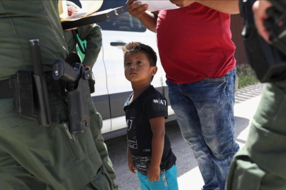 Un niño y sus padres, procedentes de Honduras, son retenidos por una patrulla policial cerca de la frontera de EEUU con México en Misión (Tejas), el 12 de junio pasado. /-JOHN MOORE