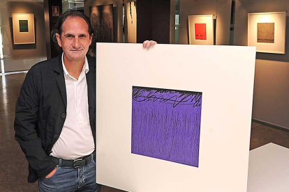 Gerardo Ibáñez sujeta una de las pinturas que componen 'En clave de FA', en la sede del Colegio de Arquitectos Técnicos.-Israel L. Murillo