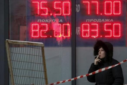Una mujer, ante un panel que muestra el cambio del rublo ante el euro y el dólar, en Moscú.-REUTERS / SERGEI KARPUKHIN
