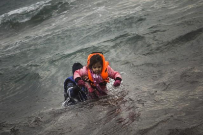 Un hombre ayuda a un niño cuyo barco ha naufragado este domingo en el Egeo.-AFP / Santi Palacios / AP
