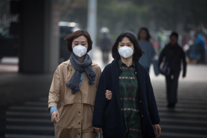 Dos mujeres con mascarilla caminan por la calle en Pekín (China).-EFE