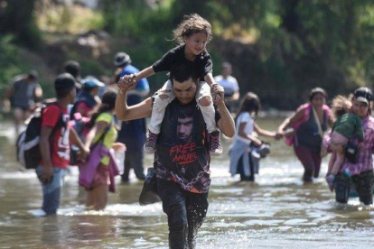 Varios migrantes cruzan el río Suchiate con sus hijos en brazos.-JOHAN ORDONEZ (AFP)