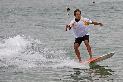 La antorcha olímpica surfea en las playas de Río.-AP / CHARLIE RIEDEL