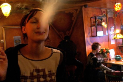 <em>Una turista fuma un porro en un 'coffeeshop' de Amsterdam.