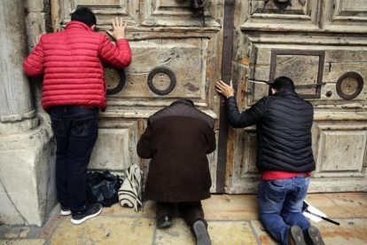 Peregrinos rezan en al puerta del Santo Sepulcro, cerrado.-/ AP / MAHMOUD ILLEAN