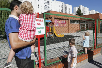 Un padre con su hijo y otros niños observan desde el exterior la guardería donde se exige que no se cierre.-SANTI OTERO