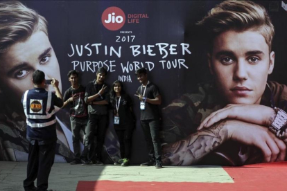 Varios jovenes indios se toman una fotografia con un cartel que publicita la gira mundial del cantante canadiense Justin Bieber antes de su concierto en el estadio Dnyandeo Yashwantrao Patil  en Bombay (India).-EFE / DIVYAKANT SOLANKI