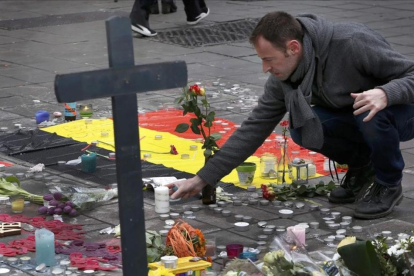 Un hombre deja flores en el tributo a las víctimas de los atentados de Bruselas-FRANCOIS LENOIR
