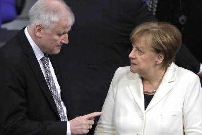 Seehofer (izq) habla con Merkel en el Parlamento alemán, en Berlín, el 14 de marzo.-AP / MARKUS SCHREIBER