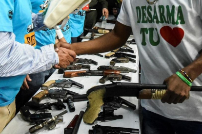 Un miembro de una banda entrega su arma en una ceremonia en Cali, el pasado julio-AFP / LUIS ROBAYO