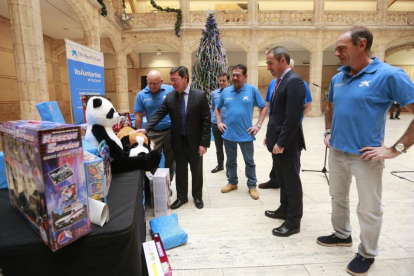 César Rico y Manuel Bilbao observan junto con klos voluntarios de ‘la Caixa’ los regalos que los niños recibirán estas navidades.-RAÚL OCHOA