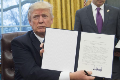 Trump muestra su firma sobe la orden de retirada del acuerdo de comercio Transpacífico.-SAUL LOEB / AFP