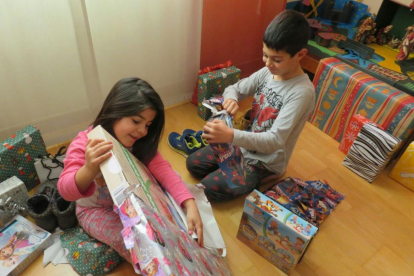 Dos hermanos disfrutan abriendo sus regalos de Reyes.-ECB