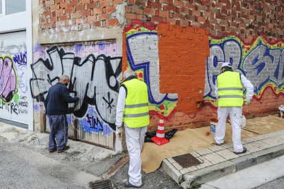 Trabajadores de los planes de empleo, de anteriores ejercicios, limpiando una pintada vandálica.