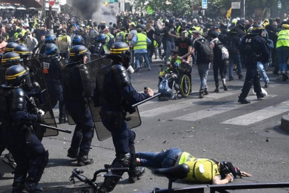 <em>Una manifestante yace en el suelo durante los choques entre la policía y los 'chalecos amarillos' este sábado en París