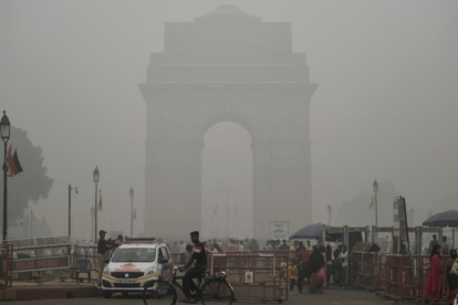 <em>Turistas visitan la Puerta de la India bajo una fuerte niebla de polución, este domingo en Nueva Deli.