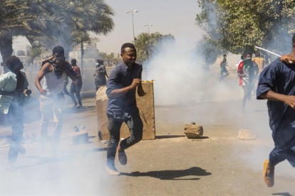 Manifestantes se protegen de los gases lacrimógenos de las fuerzas de seguridad en Jartum.-EFE