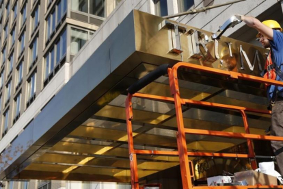 Un operario retira el nombre de la fachada de un edificio de lujo conocido hasta ahora como Trump Place, en Nueva York, el 16 de noviembre.-AP