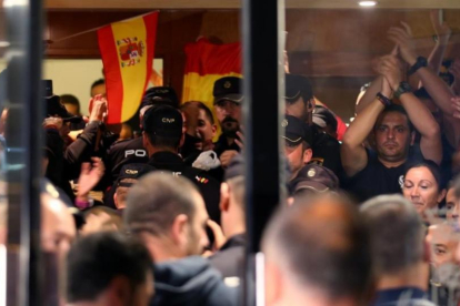 Policías nacionales, en la entrada del hotel de Pineda en el que están alojados, se enfrentan a los ciudadanos que protestan fuera.-ALBERT GEA (REUTERS)