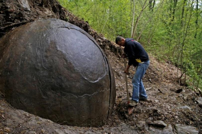 Suad Keserovic limpia la esfera de piedra en Podubravije, cerca de Zavidovici (Bosnia), el 11 de abril.-REUTERS / DADO RUVIC