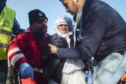 Voluntarios ayudan a una mujer anciana de Afganistán tras desembarcar con otros refugiados en Skala Sykaminias, en Lesbos, este miércoles.-AP / MSTYSLAV CHERNOV