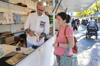 Jesús de la Gándara exhibe su nueva obra, ‘El reto de la felicidad’, a una visitante durante la Feria del Libro en el Paseo del Espolón.-RAÚL G. OCHOA