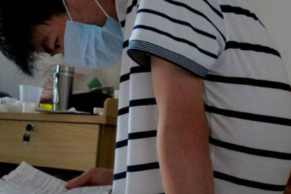 Li Haiqing, de 26 años, leyendo el prospecto farmacéutico de uno de los medicamentos que debe tomar a causa de su enfermedad.-BBC WORLD / PEKÍN