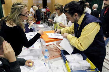 Un cartero entrega en una mesa electoral los votos por correo.-EL MUNDO