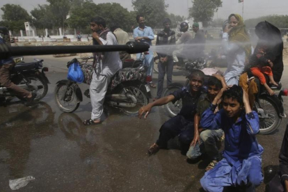 Voluntarios pulverizan a la gente en Karachi.-FAREED KHAN