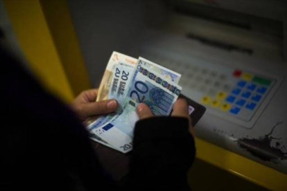 Una mujer saca dinero de un cajero automático. ECB