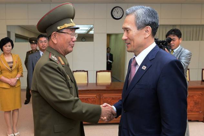 El ministro surcoreano de Unificación, Kim Kwan-jin, a la derecha, da la mano a Hwang Pyong So, responsable norcoreano, tras alcanzar el acuerdo para rebajar la tensión.-AP