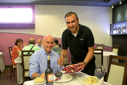 PLATOS CASEROS. José Luis Toral sirve un plato de cecina a Hansen  en el comedor del restaurante Felu, de Portillo (Valladolid).-M. T.