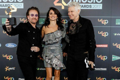 El cantante Bono y el bajista Adam Clayton, junto a Penélope Cruz, en los Premios de Música Los 40.-EFE / EMILIO NARANJO