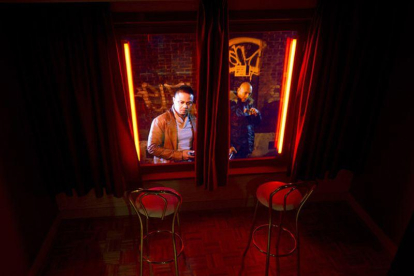Unos visitantes miran desde fuera un escaparate rojo en el museo de la prostitución del Barrio Rojo de Amsterdam.-EVERT ELZINGA (AP)