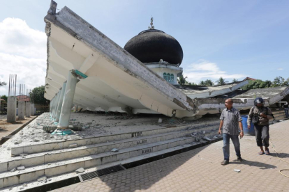 Dos vecinos pasan junto a una mezquita dañada por el terremoto, en Meuredu (Pidie Jaya).-REUTERS / ANTARA FOTO