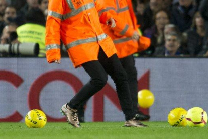Empleados del Barça retiran los balones amarillos lanzados por un sector del público.-JORDI COTRINA