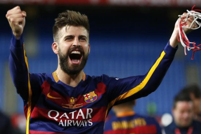 Piqué, con un trozo de red cortada de la portería del Calderón, festeja la Copa.-AP / FRANCISCO SECO