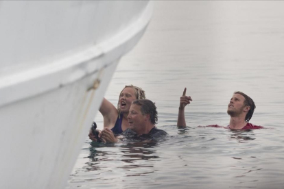 Activistas en el agua intentan impedir la marcha de un ferri que traslada a refugiados de vuelta a Turquía en el puerto de Mitilene (Grecia), en Lesbos.-AP / PETROS GIANNAKOURIS