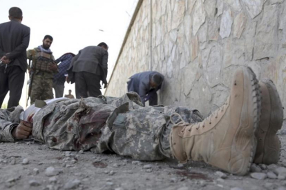 Militares inspeccionan el cadáver de un miliciano en la sede del Ministerio del Interior afgano, en Kabul.-/ RAHMAT GUL