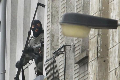 Un agente utiliza una cámera extendida para espiar en el interior de un piso, en Molenbeek, este lunes.-REUTERS / YVES HERMAN