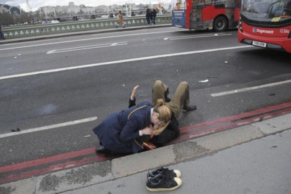 Una mujer atiende a un herido en el puente de Londres.-REUTERS / TOBY MELVILLE