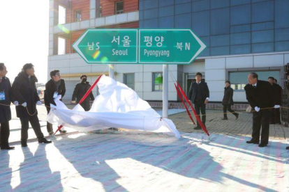 Oficiales norcoreanos y surcoreanos destapan dos señales que indican la dirección de las capitales de ambos países en la estación de tren de Panmun en Kaesong.-EPA / KOREA POOL
