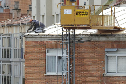 Un trabajador, sobre el tejado de una vivienda.-ISRAEL L. MURILLO