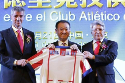 Wang Jianlin, presidente del grupo Wanda, sostiene una camiseta del Atlético de Madrid entre el director general, Miguel Ángel Gil, y el presidente, Enrique Cerezo, tras comprar un 20% del club por 45 millones de euros.-REUTERS / JASON LEE