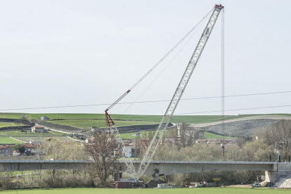 Una grúa de grandes dimensiones ha empezado a descolgar vías, barandillas y otros elementos del puente.-ISRAEL L. MURILLO
