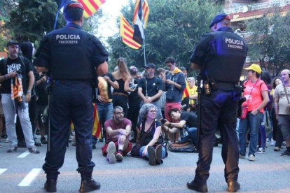 Dos agentes de los Mossos d’Esquadra, ante un grupo de manifestantes que organizó una sentada ante la sede de la Guardia Civil en la Travessera de Gràcia de Barcelona, el pasado 20 de septiembre.-MIQUEL CODOLAR ACN