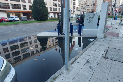 La plataforma de cemento sobre la que se ha colocado el cargador eléctrico frena el flujo de agua de lluvia que discurre por la avenida e impide que llegue hasta el sumidero.