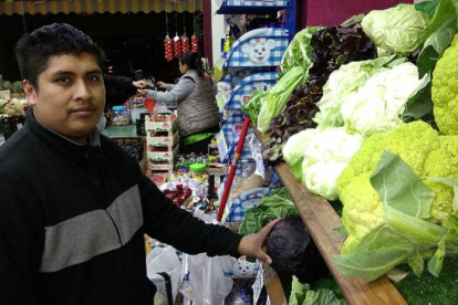 Éverson Fernández e Ibeth Kathia Suárez, al fondo, en su comercio de frutas y verduras de Barcelona.-EL PERIÓDICO