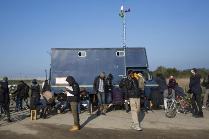 Inmigrantes del campamento francés de Calais usan teléfonos móviles junto a un camión que ofrece conectividad.-JACK TAYLOR